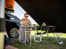 Someone enjoying making dinner at camp outside of their TentBox with the KitchenBox all in one camp kitchen