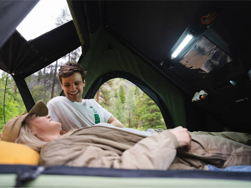 Couple lounging inside the Cargo 2.0, smiling while reading a book.

