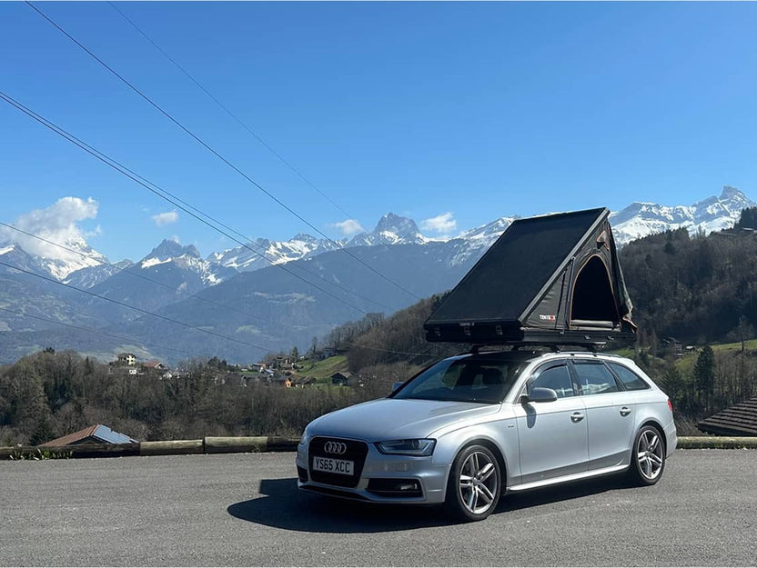 Cargo 2.0 fully set up on a silver car in the mountains, tent angled open against a scenic sky.