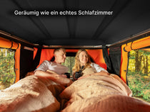   two people laying down inside a TentBox Classic roof top tent, showing off the size and space