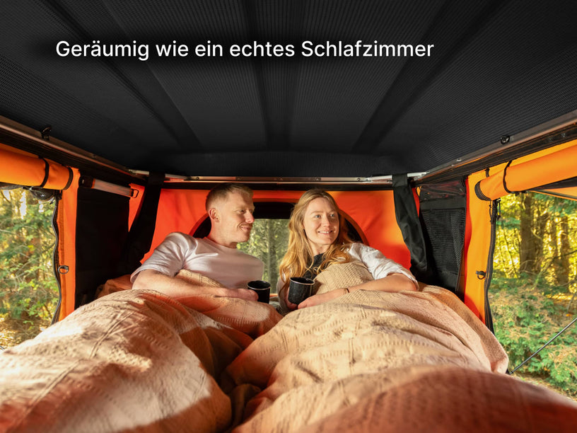   two people laying down inside a TentBox Classic roof top tent, showing off the size and space