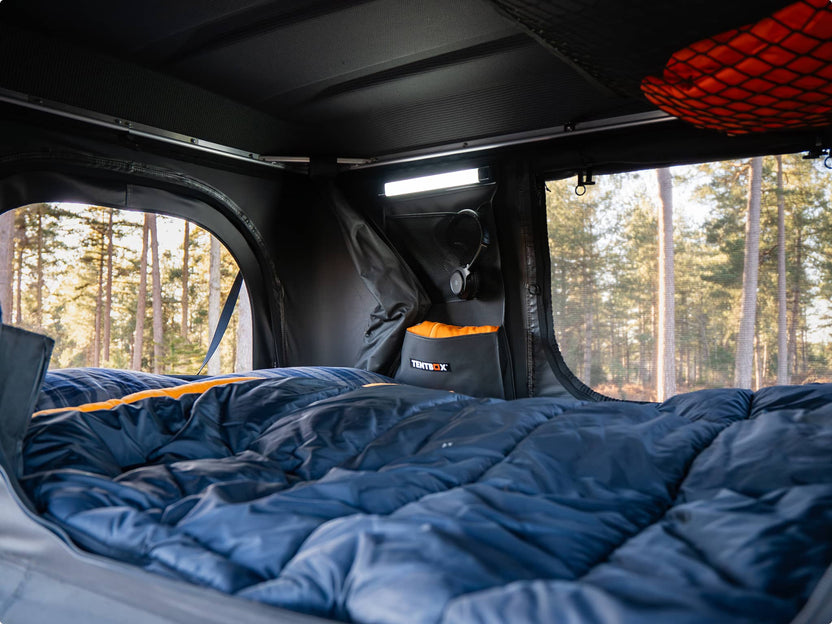 Interior view of TentBox Classic with double sleeping bags inside, forest visible through the windows