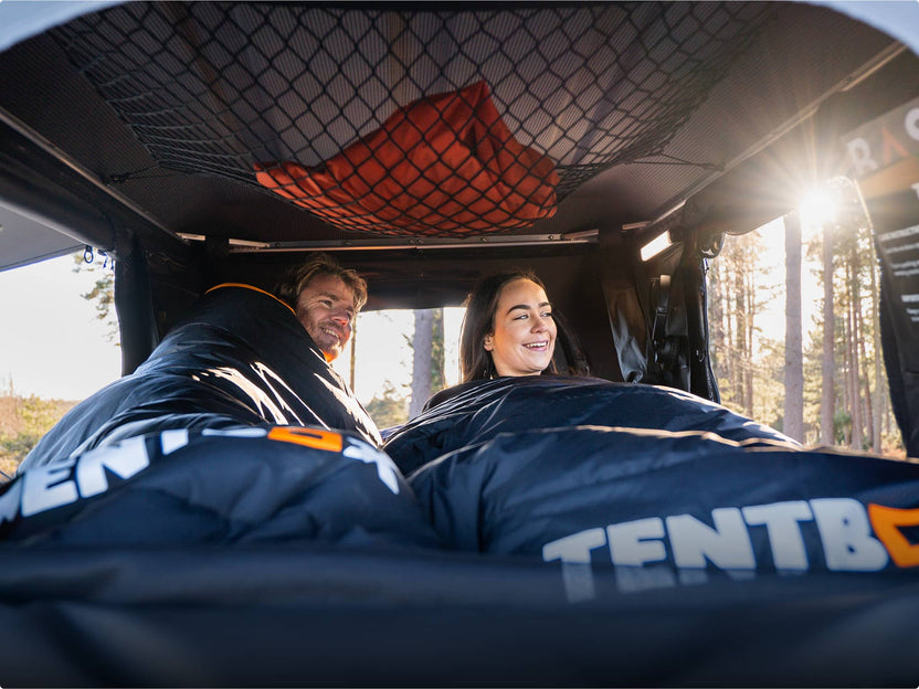 Interior of the TentBox Classic with thick sleeping bags and netted ceiling storage; light streaming in.