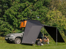 TentBox Classic fully set up with an extended awning providing shade, couple relaxing at the campsite.