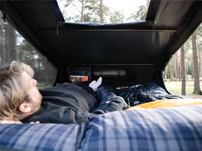 Inside view of a person relaxing in the GO, lying on a blue sleeping bag and looking out the skylight.

