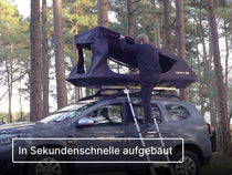Person, die ein Dachzelt auf einem Auto im Wald aufbaut
