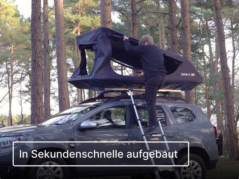 Person, die ein Dachzelt auf einem Auto im Wald aufbaut