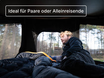 Mann, der entspannt im GO Dachzelt liegt und durch die Mesh-Fenster auf beiden Seiten den Waldblick genießt.