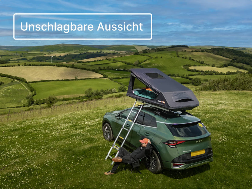 GO Dachzelt vollständig aufgebaut auf einem Auto auf einem Hügel-Campingplatz, mit ausgefahrener Leiter; im Hintergrund eine üppige Landschaft.