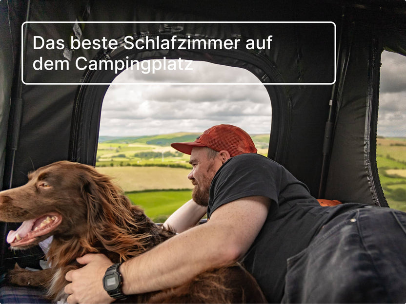 Mann und sein Hund schauen aus dem geöffneten GO Dachzelt heraus; die Stimmung ist fröhlich und gemütlich.