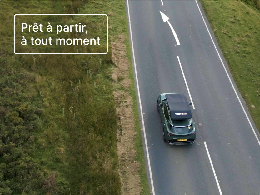 Vue aérienne d’une voiture roulant avec la tente GO fixée sur le toit, illustrant son profil mince en transit.