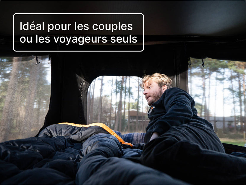Homme se relaxant à l’intérieur de la tente GO, avec les fenêtres en mesh de chaque côté, profitant de la vue sur la forêt.