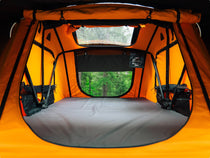 Inside view of a spacious TentBox with windows open, showing the orange and black interior.