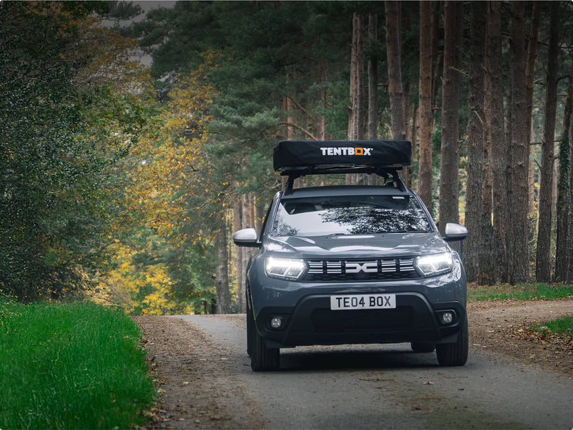 TentBox Lite 2.0 mounted on a black SUV driving through a forest trail