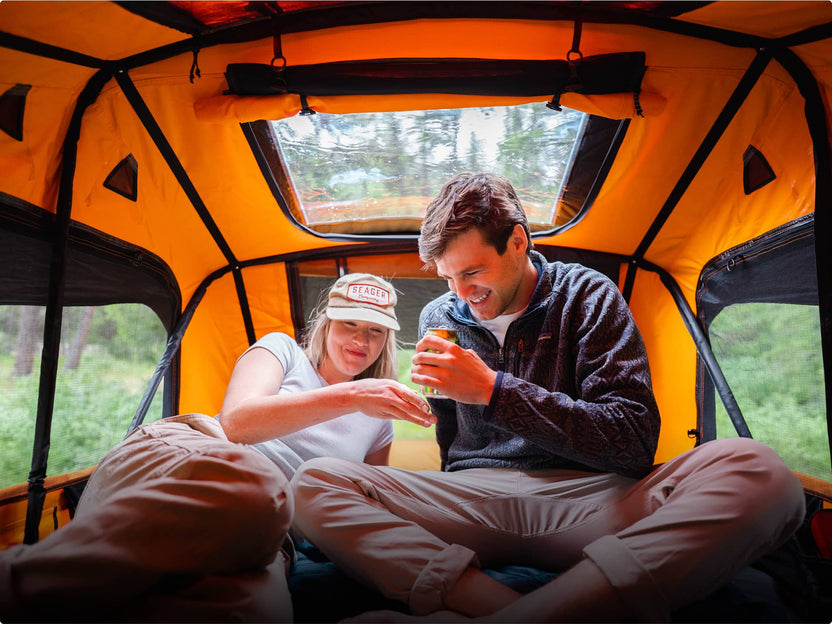 Couple enjoying a drink inside a TentBox at sunset with the roof skylight above
