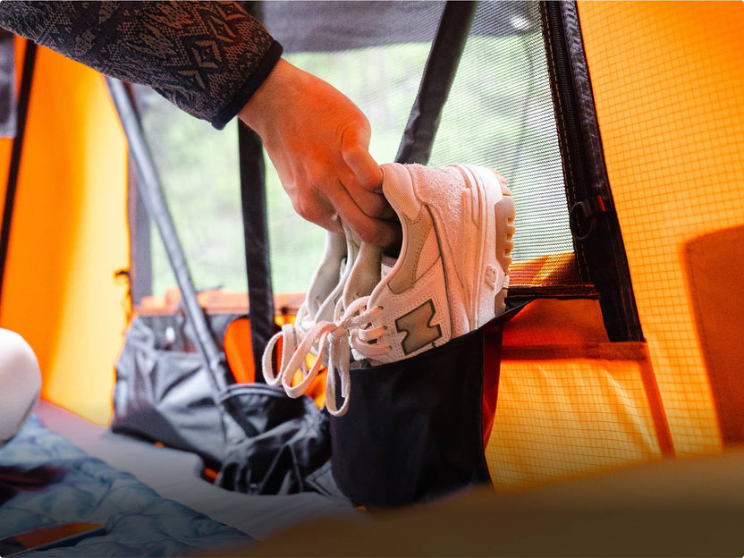 Close-up of someone storing shoes inside the TentBox, using integrated storage pockets.