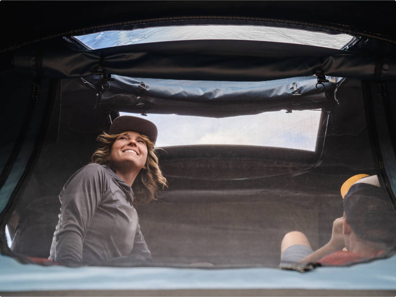Two people relaxing inside the TentBox, looking out of the skylight at the sky above