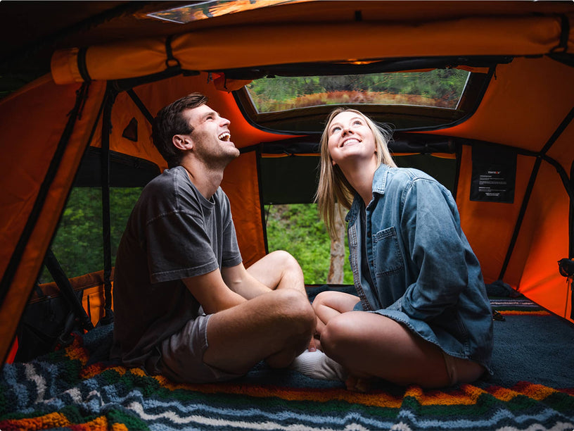 Couple laughing and enjoying the spacious orange-lit interior of the TentBox